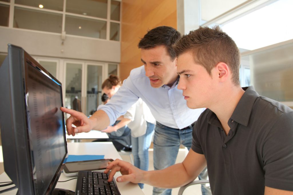 LinQuest intern looking at desktop with another person pointing to the screen
